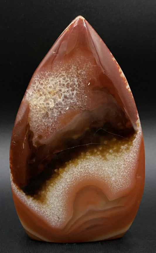 Sculptura din cristal de agat rosu pe fundal negru sub lumina artificiala