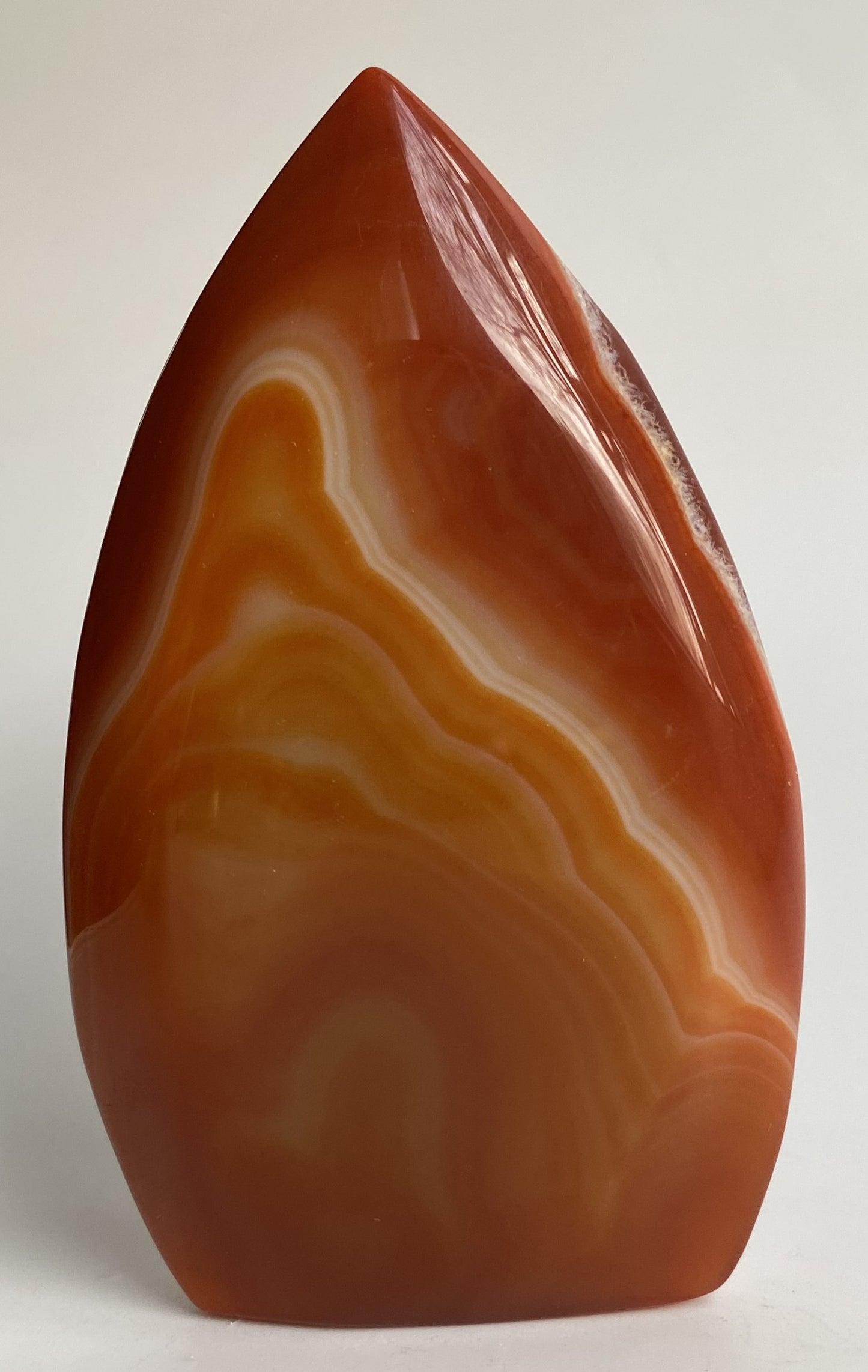 Sculptura din cristal de agat rosu pe fundal alb sub lumina naturala