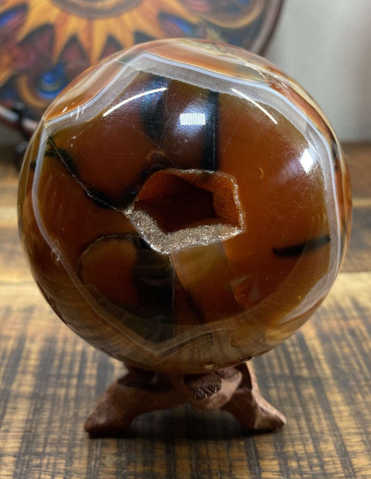 Red agate semiprecious stone sphere on wooden stand