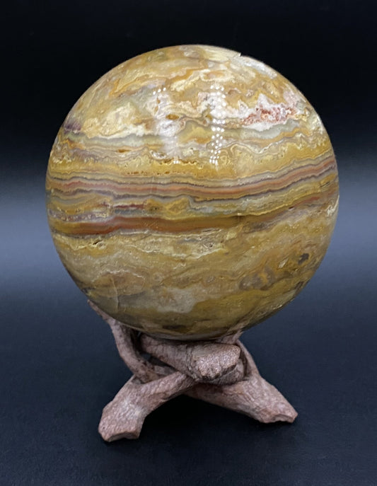 Sfera din agat thousand layers pe suport de lemn cu fundal negru sub lumina artificiala