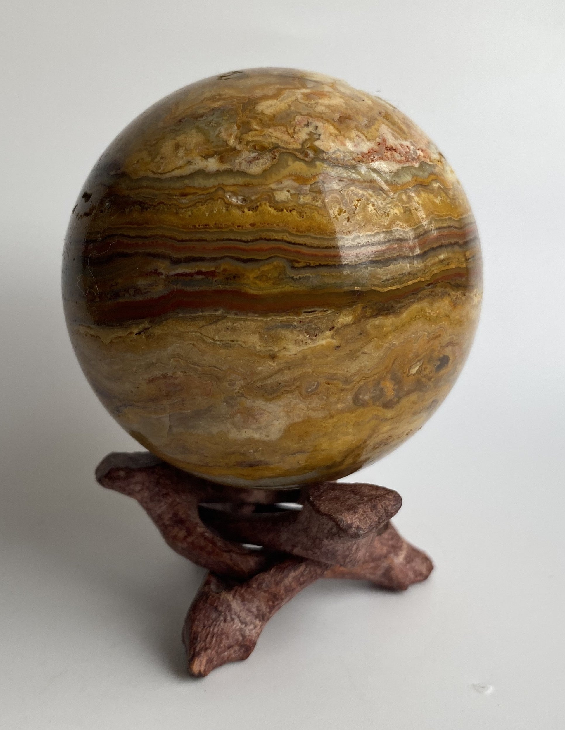 Sfera din agat thousand layers pe suport de lemn cu fundal alb sub lumina naturala