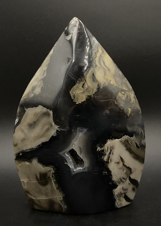 Sculptura din cristal de agat vulcanic pe fundal negru sub lumina artificiala