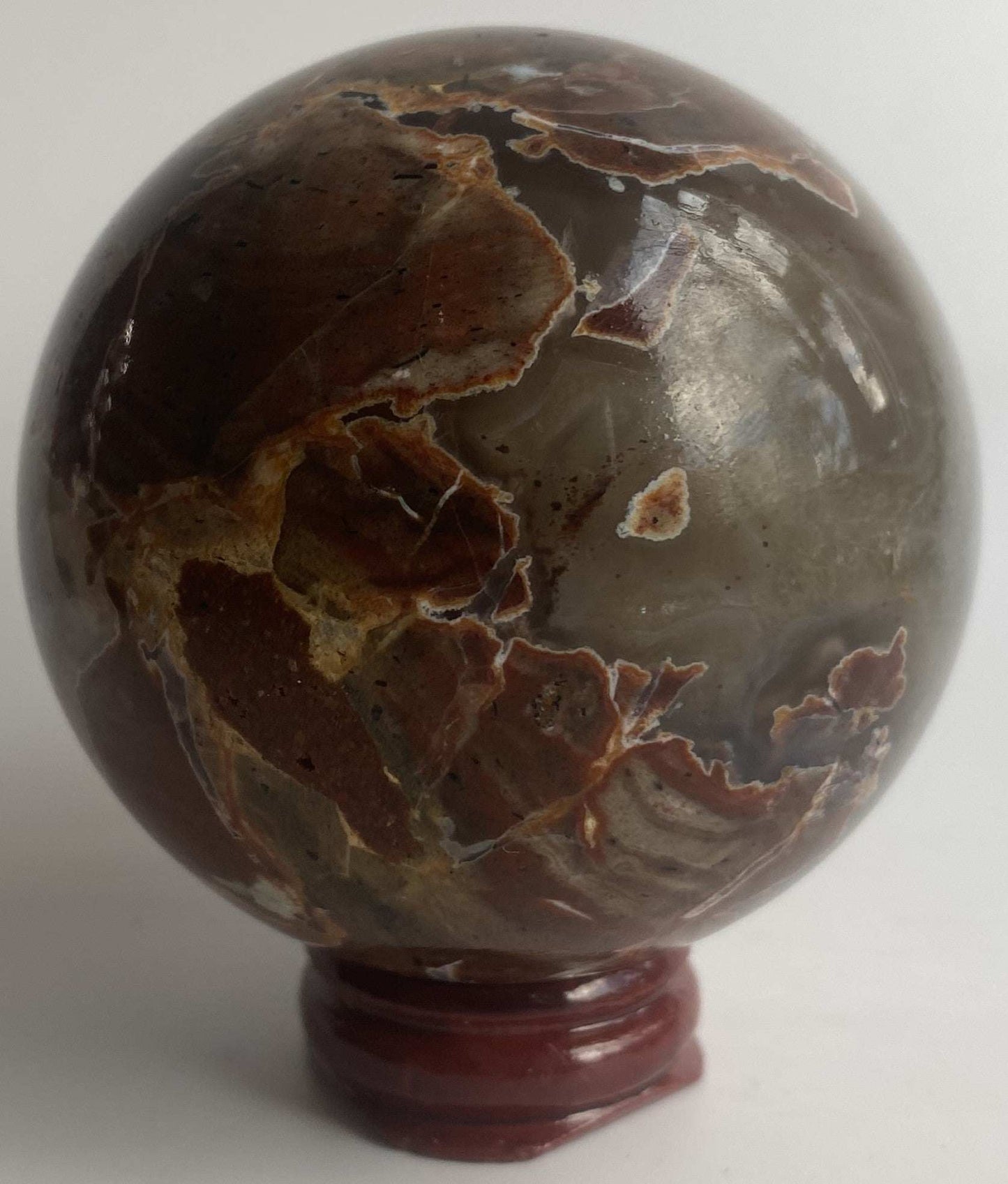 Sfera din cristal de agat vulcanic pe suport din lemn cu fundal alb
