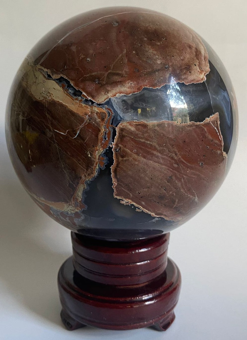 Sfera din cristal de agat vulcanic pe suport din lemn cu fundal alb