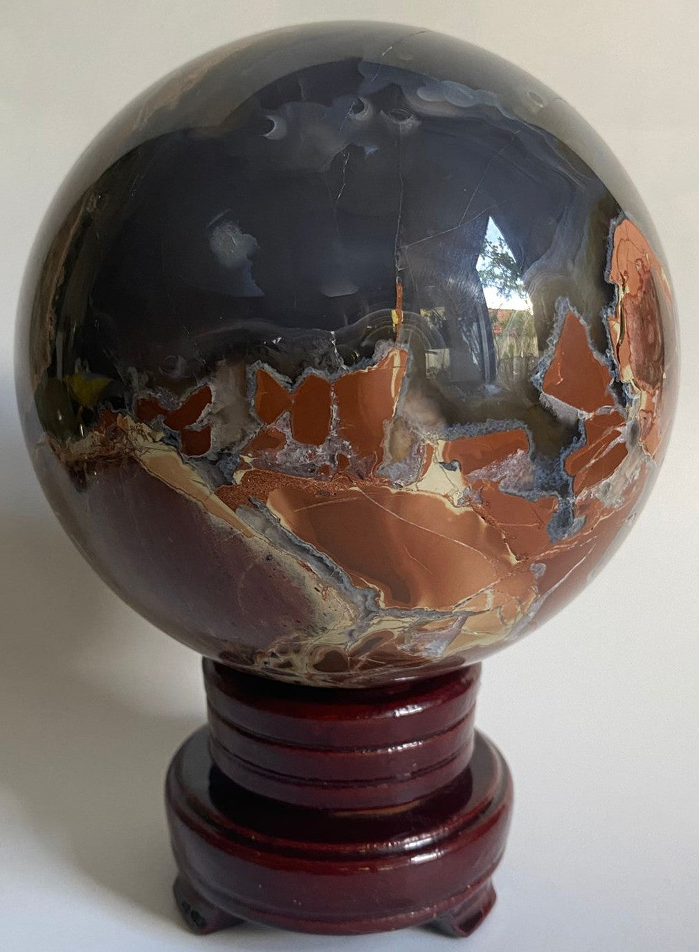 Sfera din mineral de agat vulcanic pe suport din lemn cu fundal alb