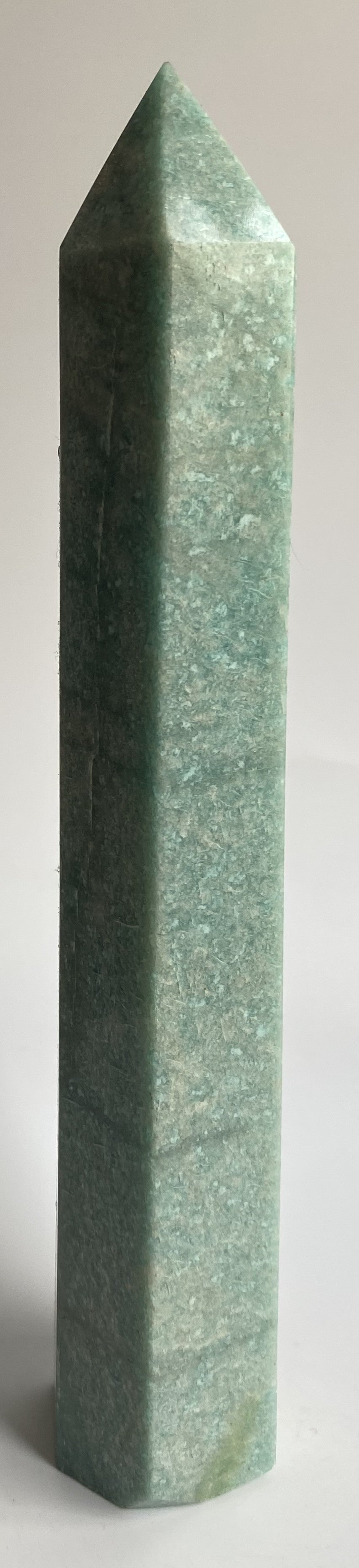 Obelisc din mineral de amazonit pe fundal alb sub lumina naturala