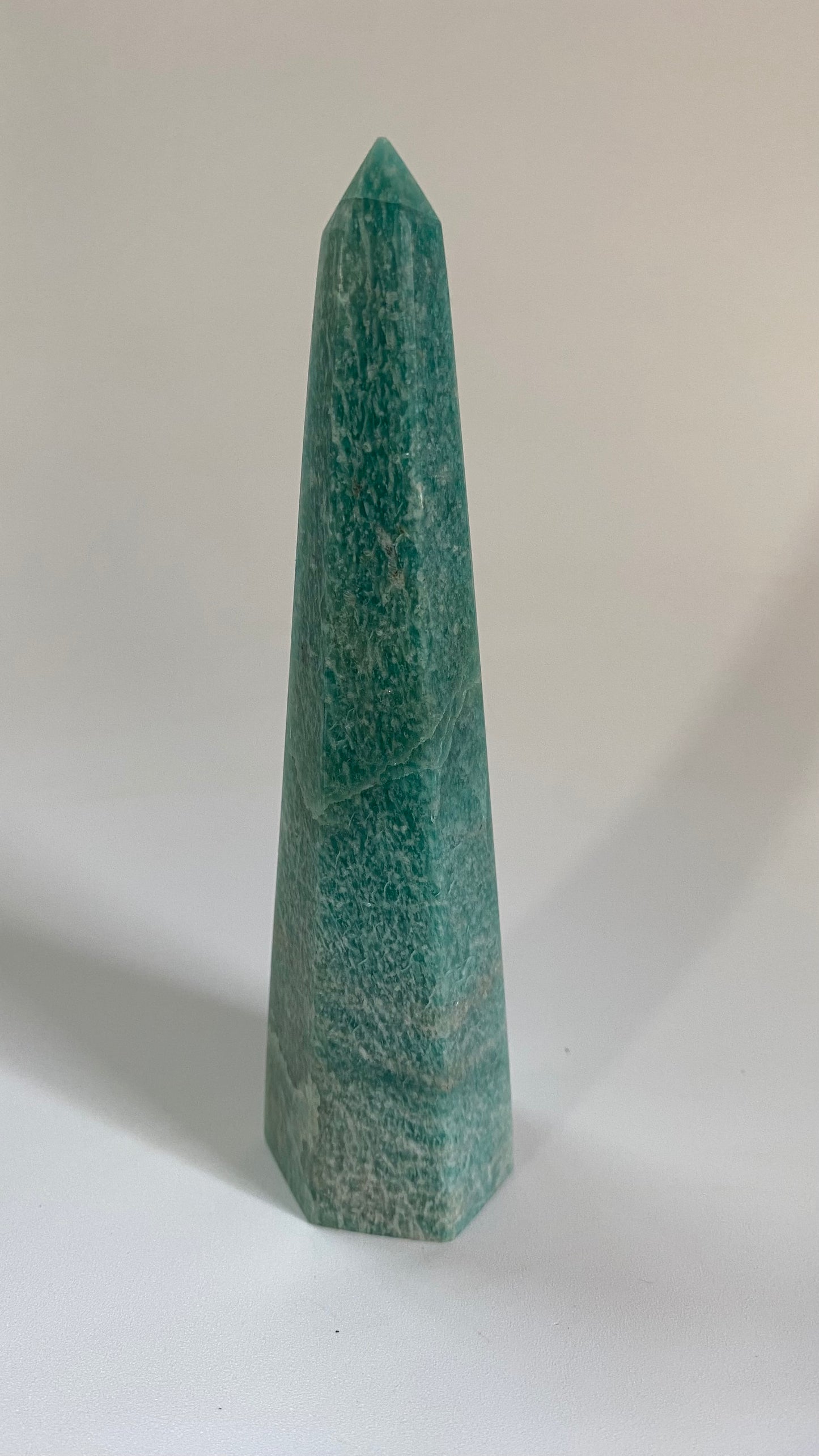 Obelisc piramidal din mineral de amazonit pe fundal alb sub lumina naturala