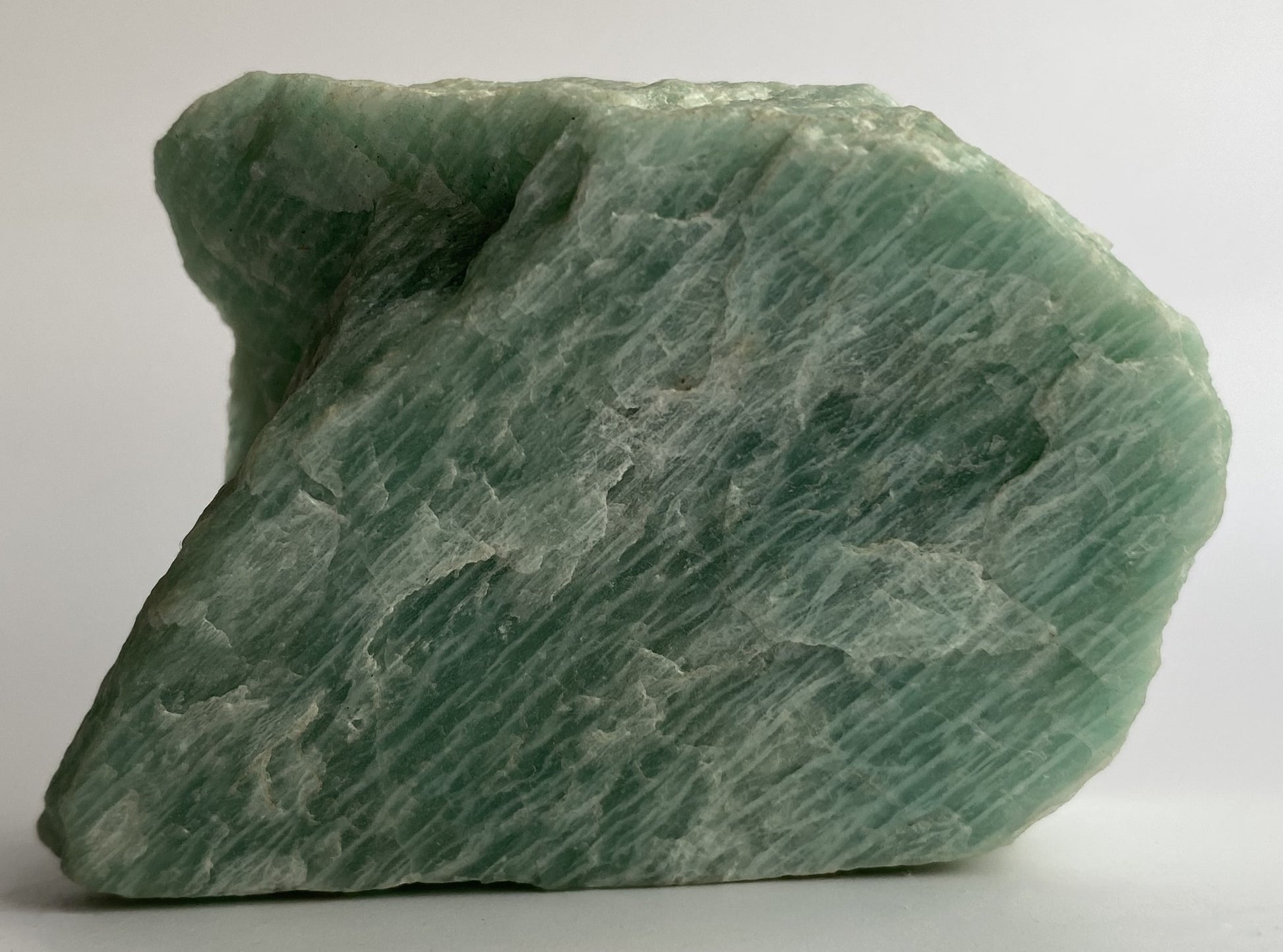 Piatra bruta din mineral de amazonit pe fundal alb sub lumina naturala