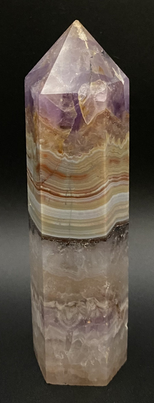 Obelisc din mineral simbiot de agat si ametist pe fundal negru sub lumina artificiala