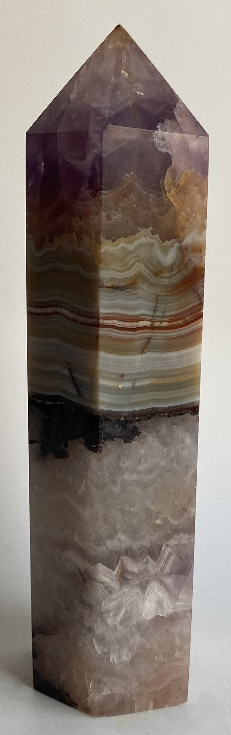 Obelisc din mineral simbiot de agat si ametist pe fundal alb sub lumina naturala