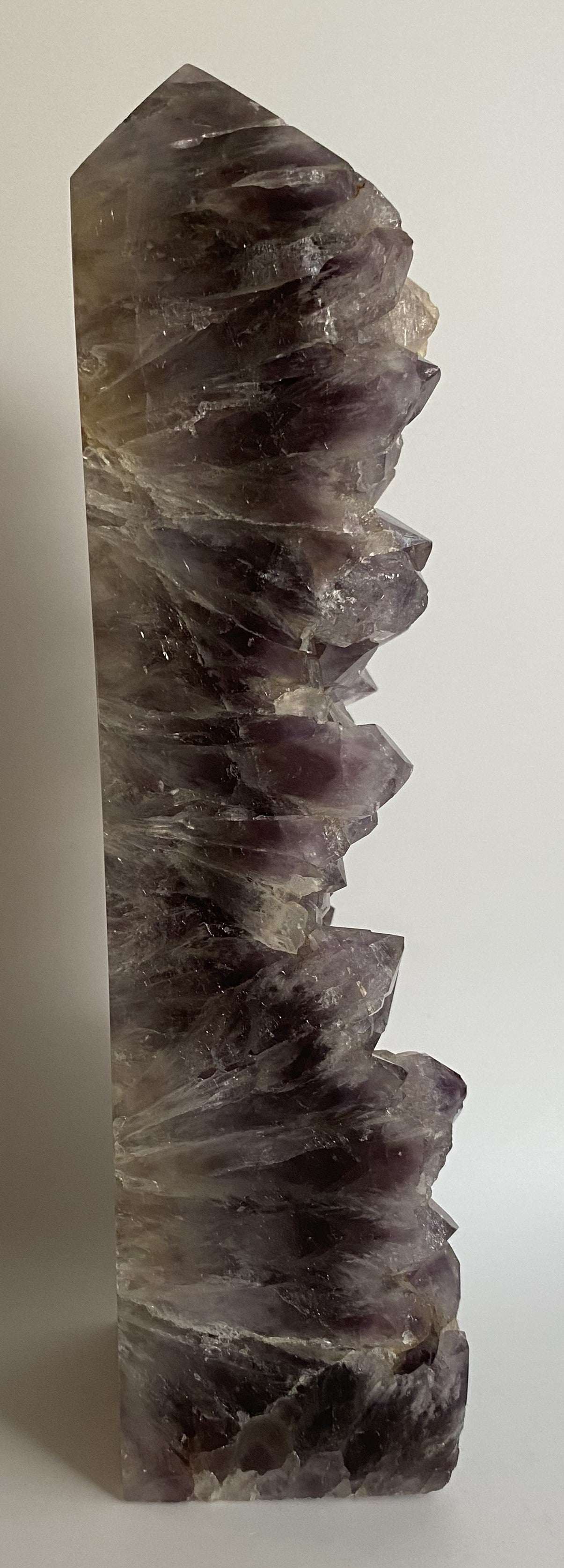 Obelisc din geoda de Ametist cu cristale mov semi-transparente pe fundal alb