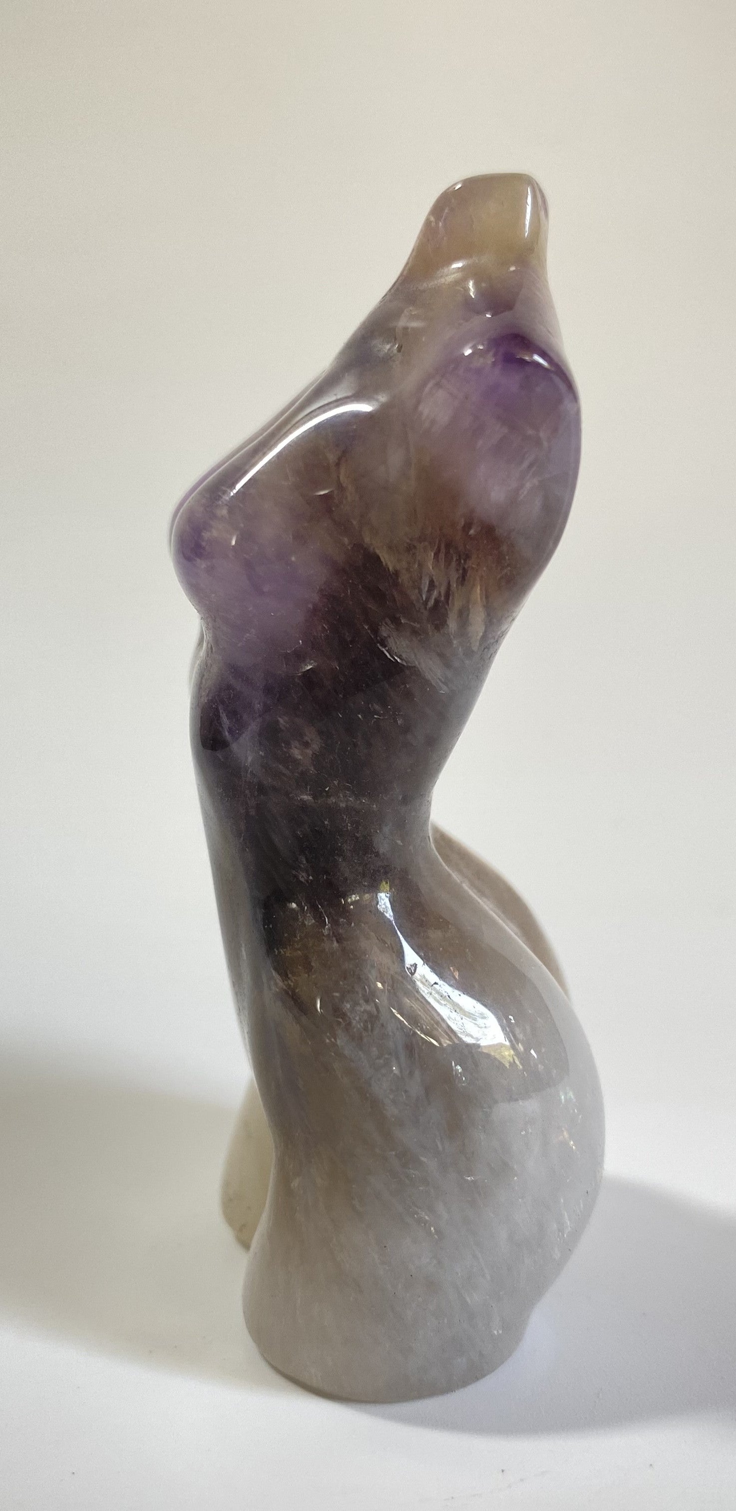 Sculptura in forma de nud din cristal de ametist chevron pe fundal alb sub lumina naturala