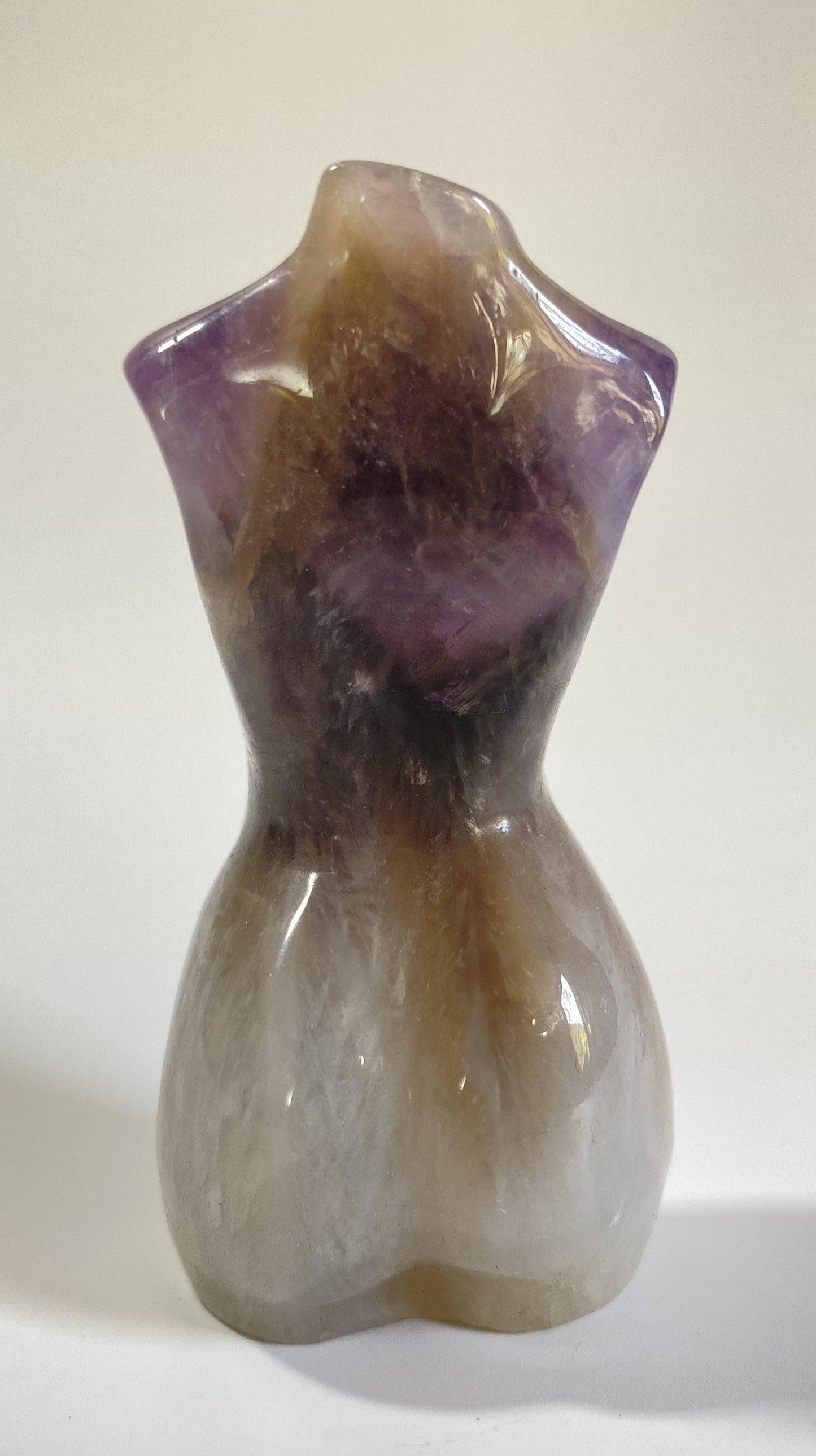 Sculptura in forma de nud din cristal de ametist chevron pe fundal alb sub lumina naturala