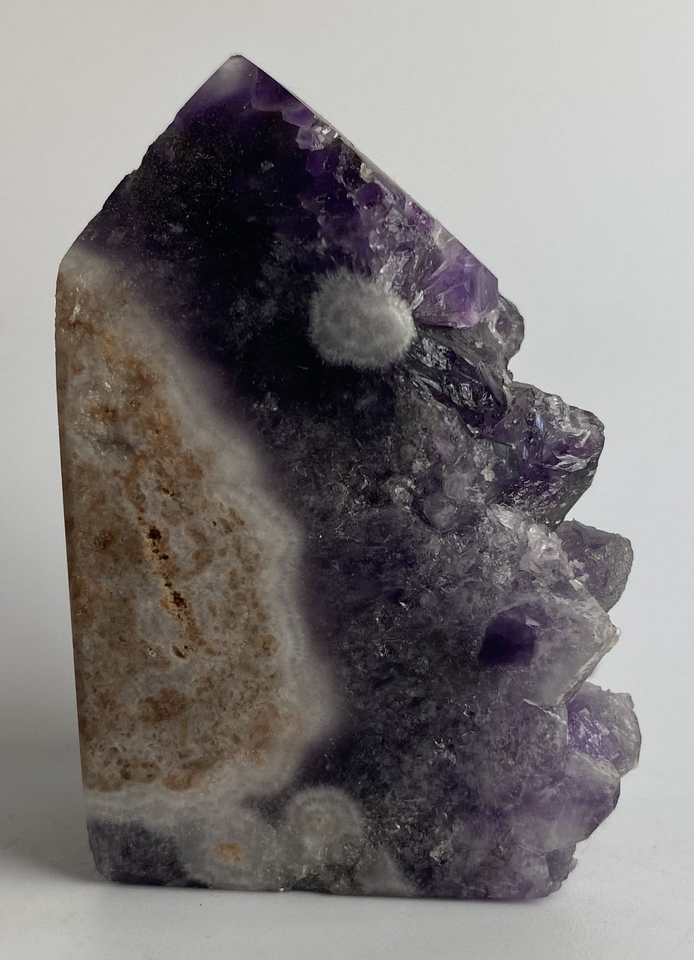 Obelisc din geoda de ametist pe fundal alb sub lumina naturala