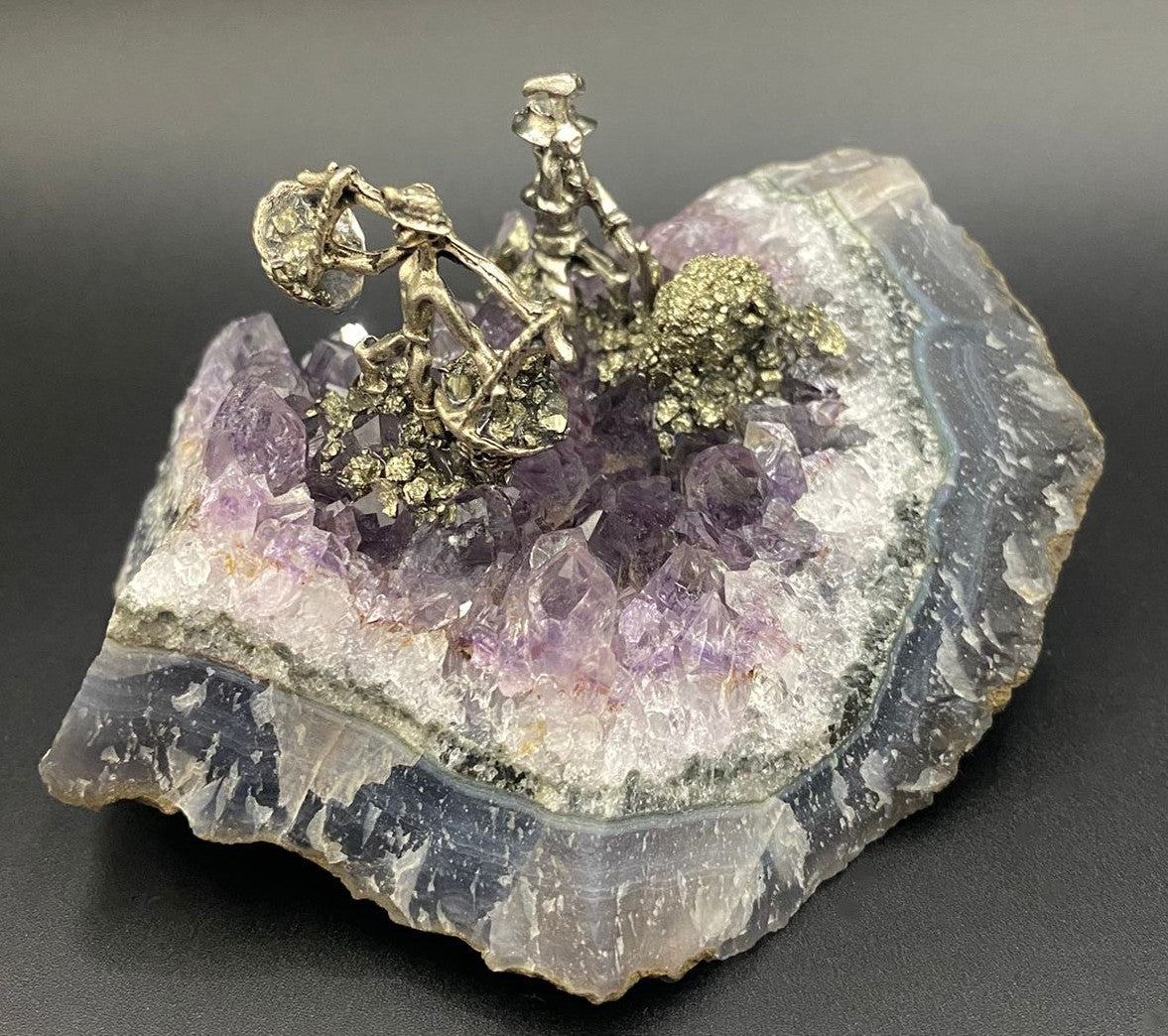 Geoda din piatra semipretioasa de ametist cu miniaturi de mineri metalice pe fundal negru