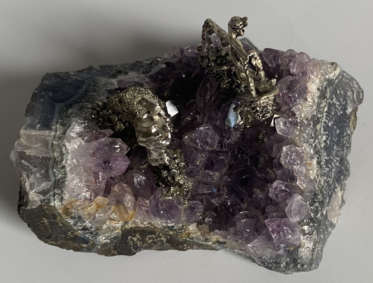 Geoda de 9.6cm din cristal de ametist cu miniaturi de mineri metalice pe fundal alb