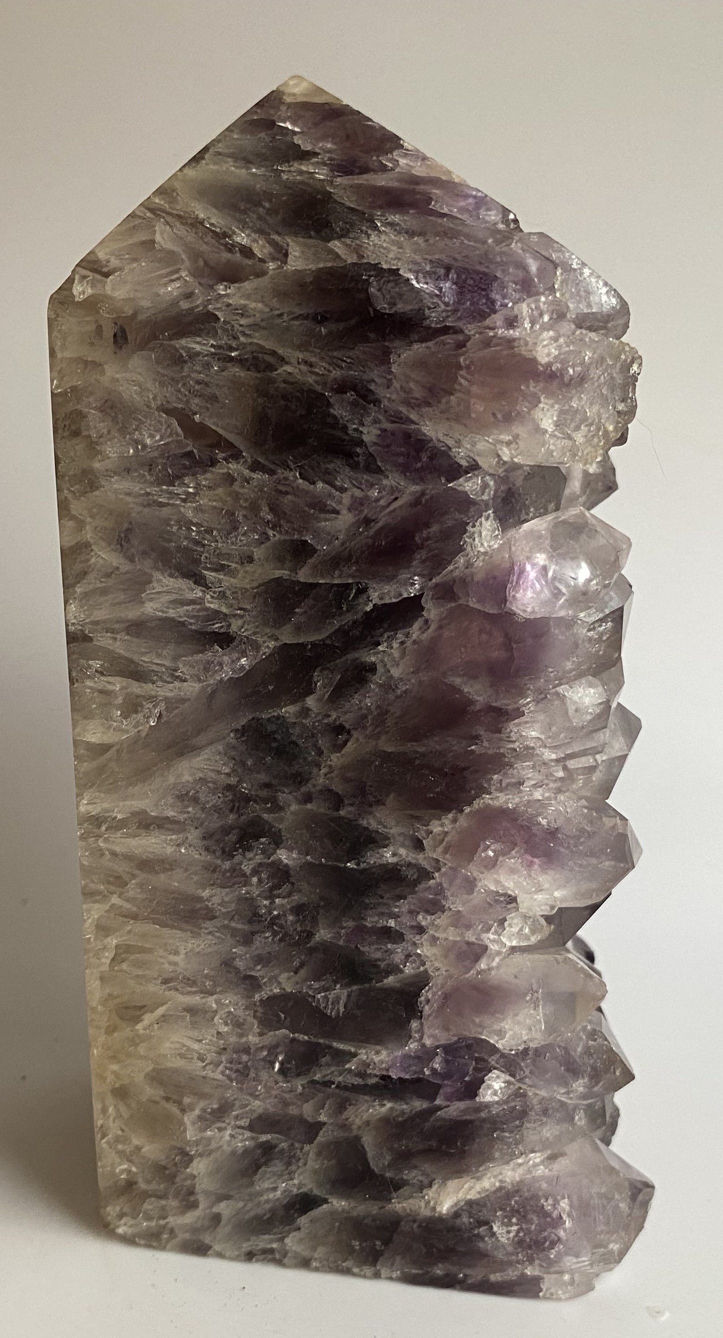 Obelisc din geoda de ametist pe fundal alb sub lumina naturala