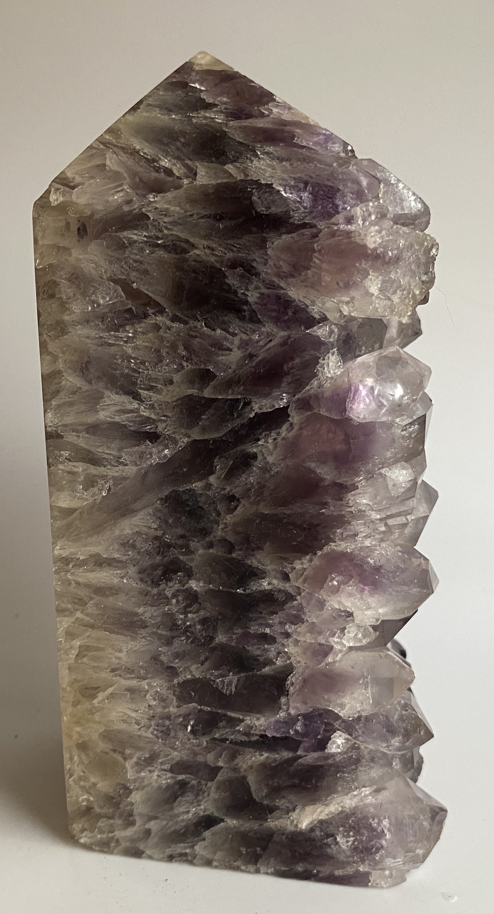 Obelisc din geoda de ametist pe fundal alb sub lumina naturala