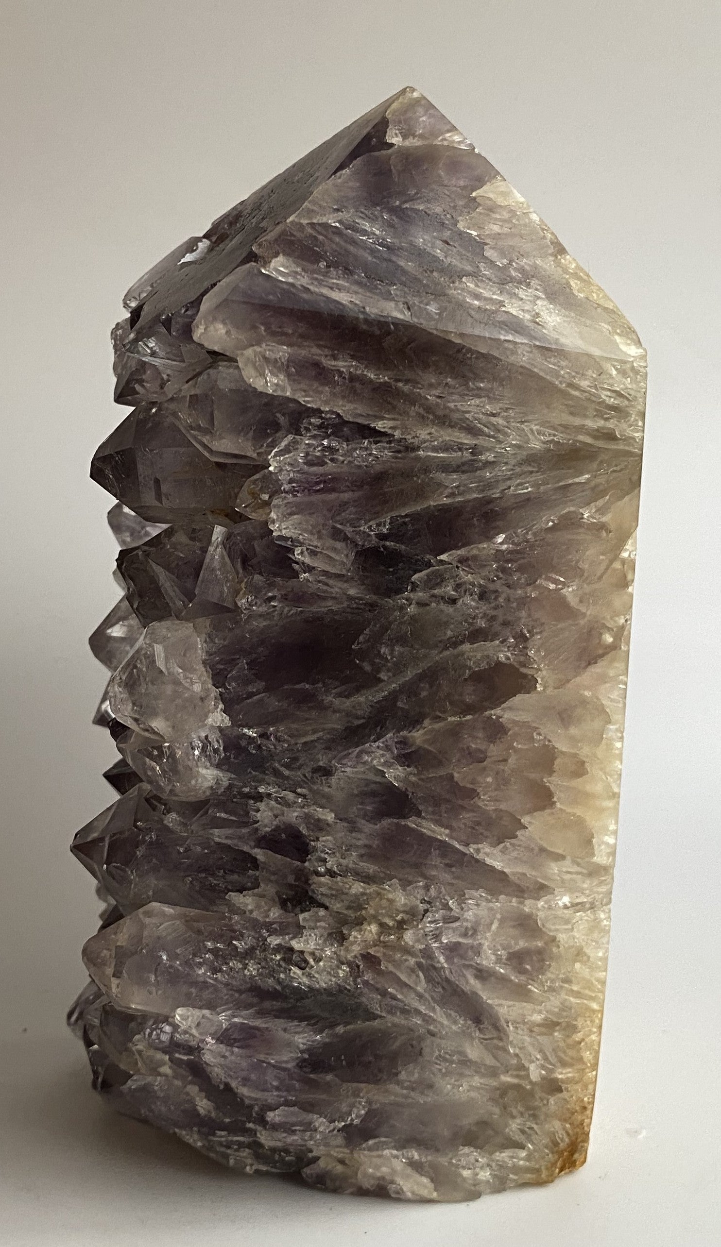 Obelisc din geoda de ametist pe fundal alb sub lumina naturala