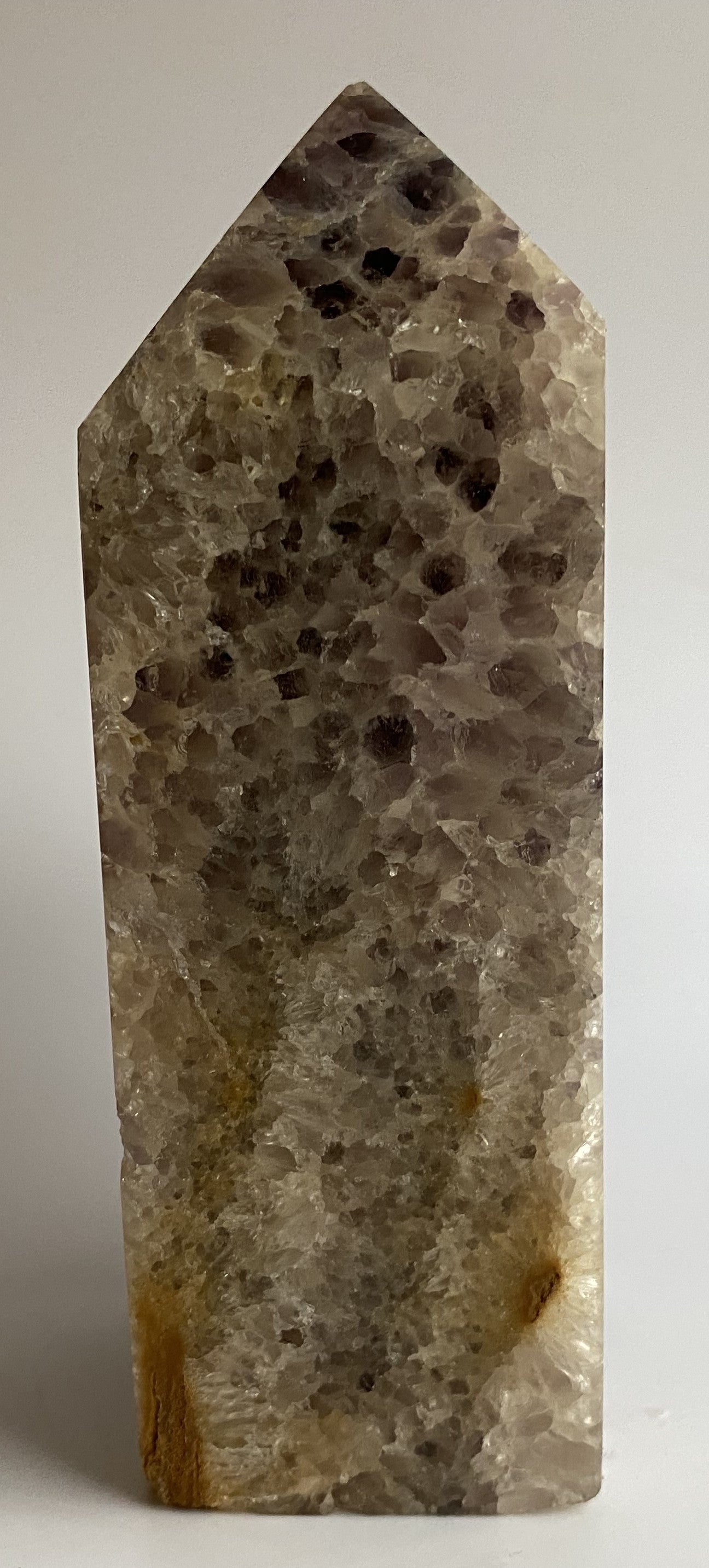 Obelisc din geoda de ametist pe fundal alb sub lumina naturala