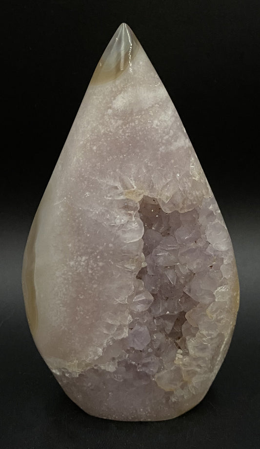 Sculptura din cristal de ametist roz pe fundal negru sub lumina artificiala