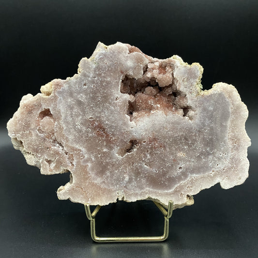 Geoda din cristal de ametist roz pe suport metalic auriu cu fundal negru sub lumina artificiala