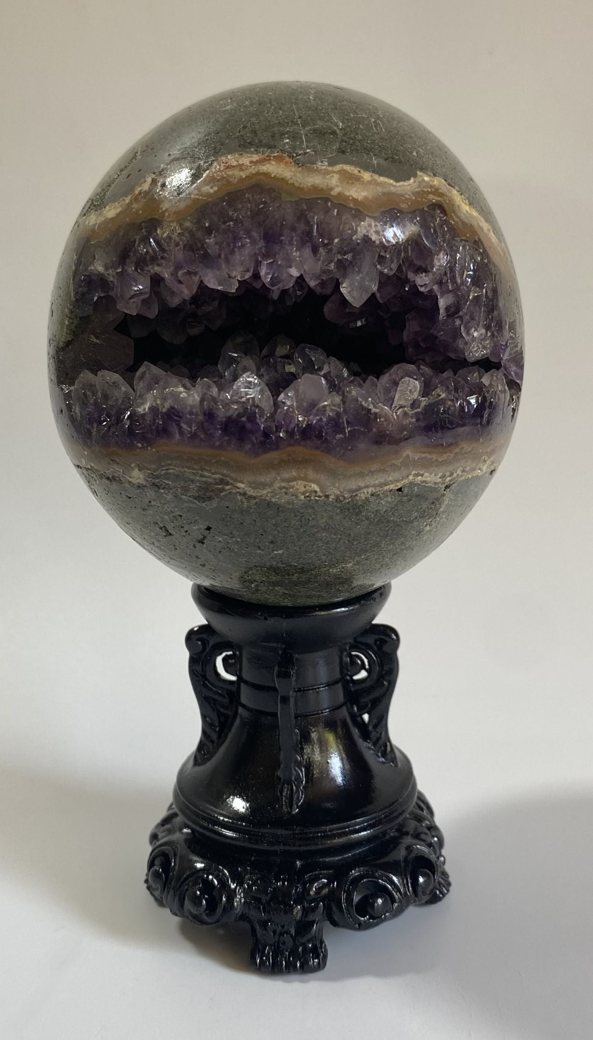 Sfera din geoda de cristal de ametist pe suport decorativ cu fundal alb