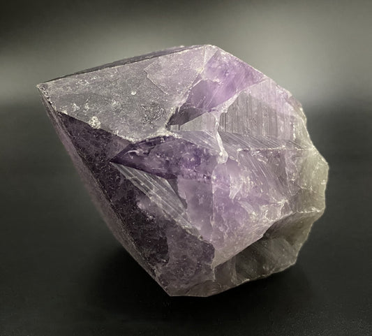 Varf brut din cristal de ametist pe fundal negru sub lumina artificiala