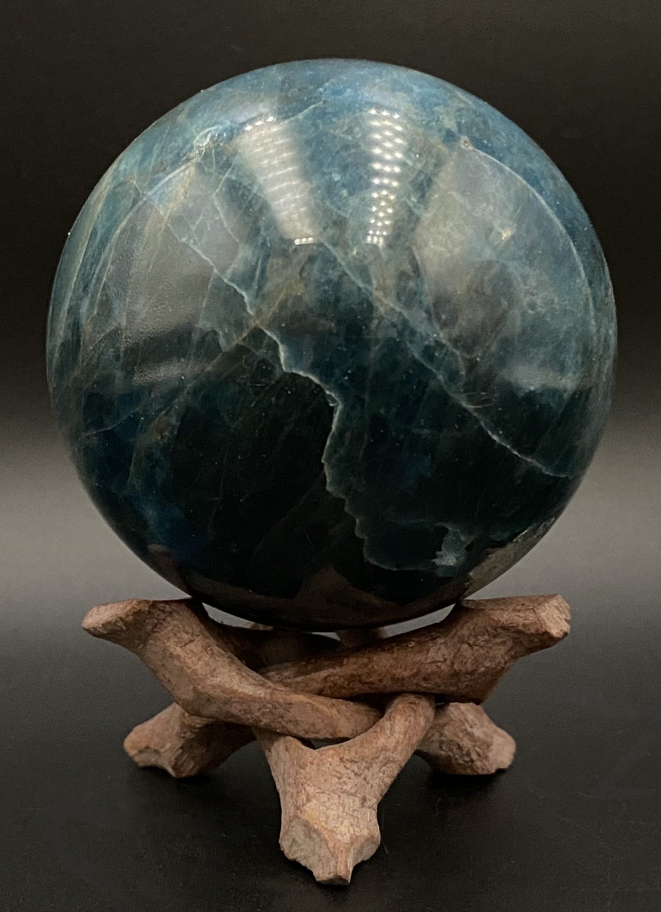 Sfera din piatra semipretioasa de apatit pe tripod din lemn cu fundal negru