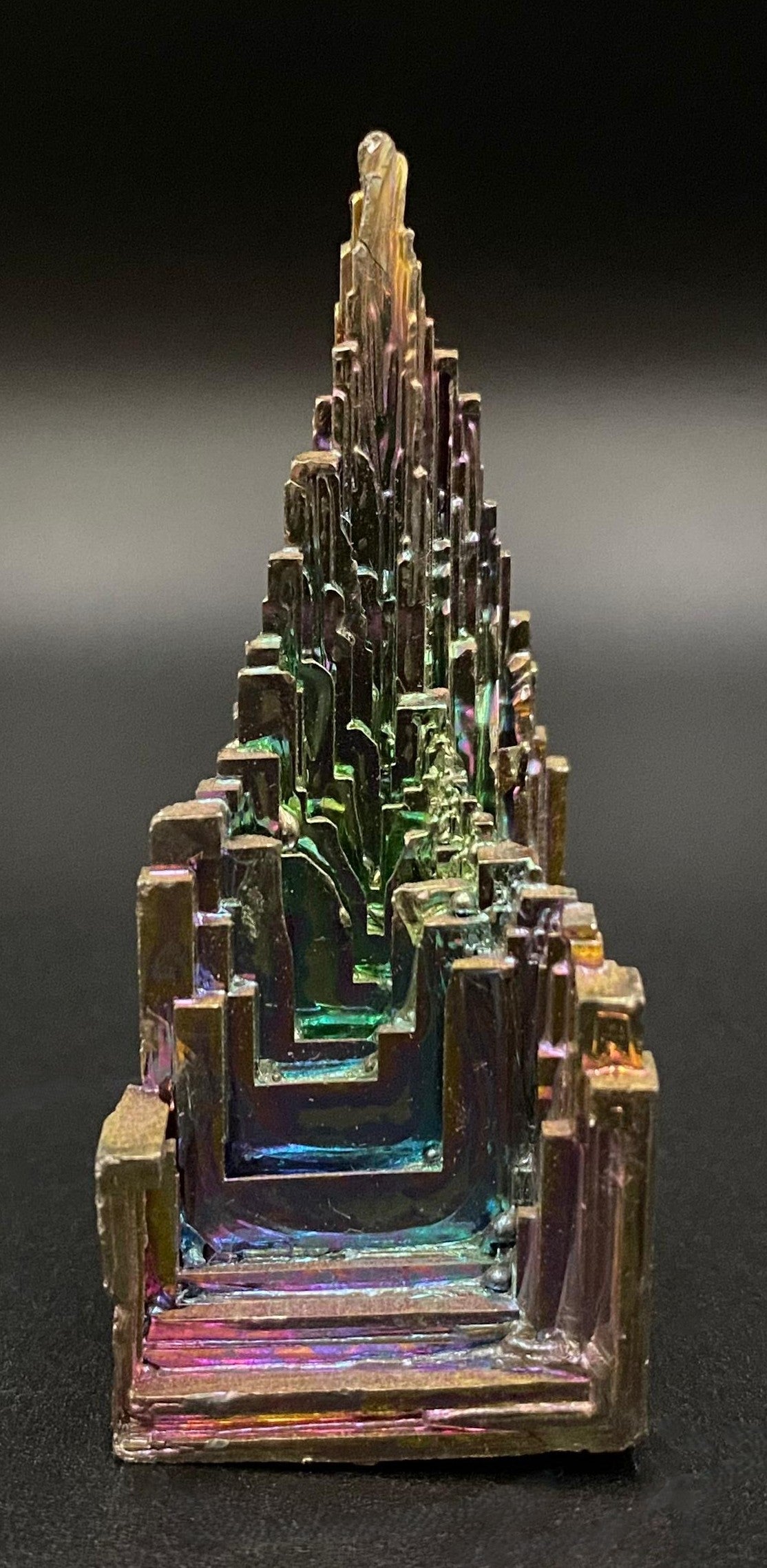 Specimen piramidal din piatra semipretioasa de bismut pe fundal negru