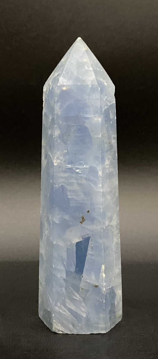 Obelisc din cristal de calcit albastru pe fundal negru sub lumina artificiala