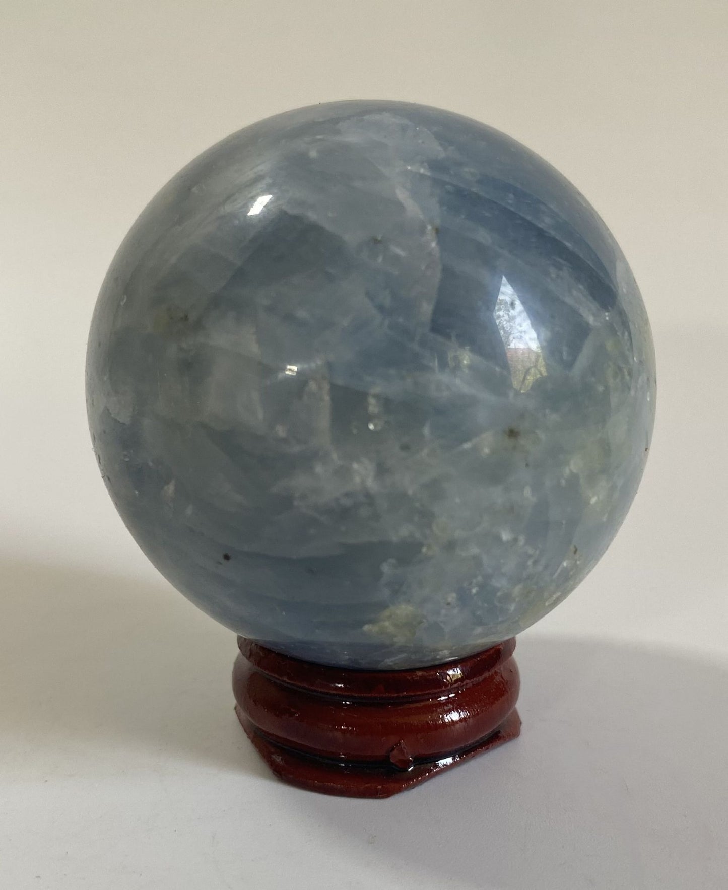 Sfera de 5.4cm din piatra semipretioasa de calcit albastru pe suport din lemn cu fundal alb