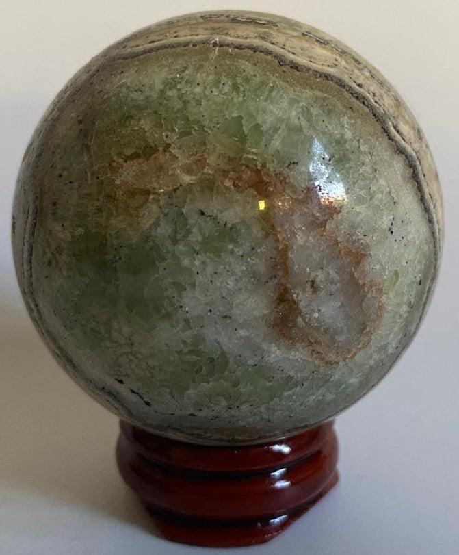 Sfera din cristal de calcit caraibe verde pe suport din lemn cu fundal alb