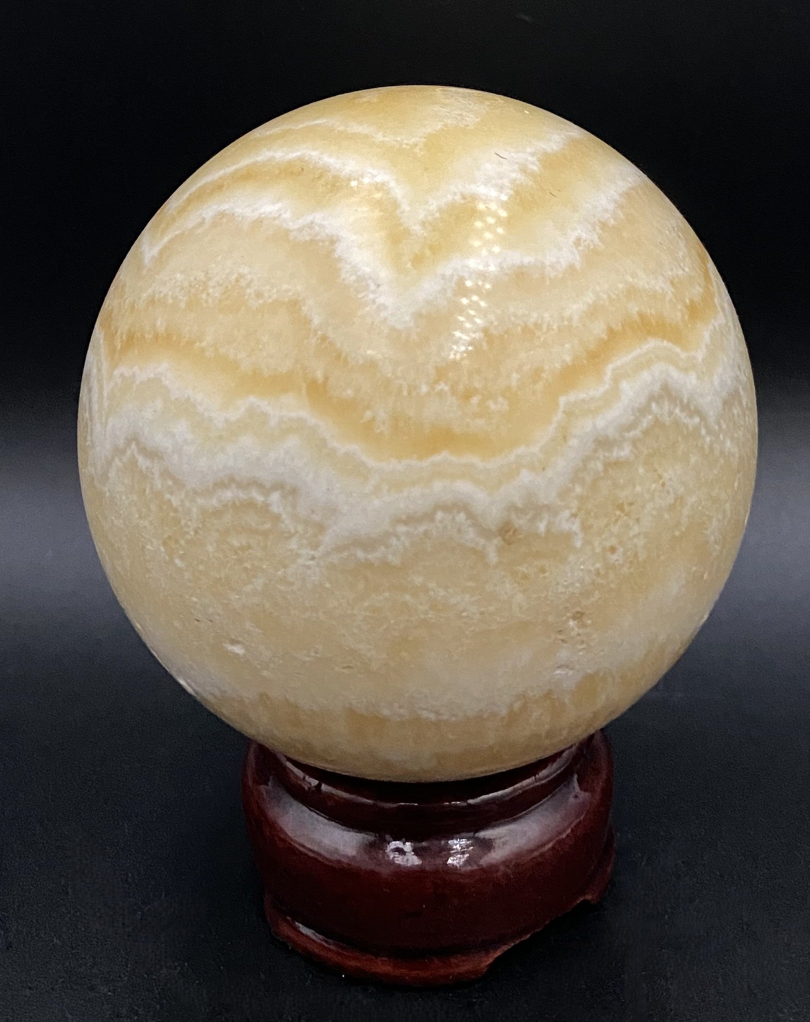 Sfera din mineral de calcit galben pe fundal negru sub lumina artificiala 