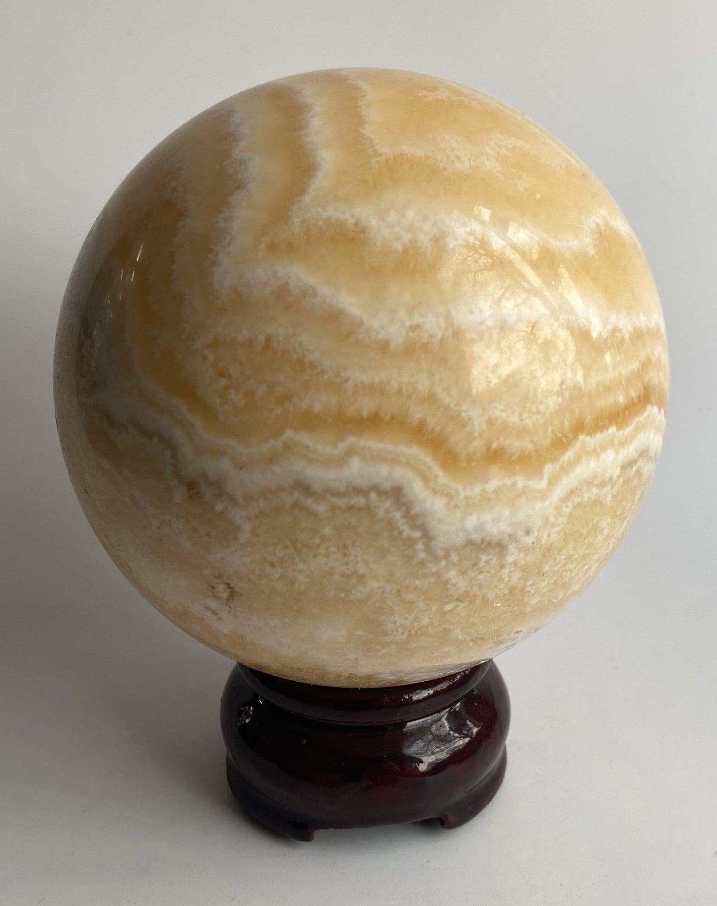 Sfera din mineral de calcit galben pe fundal alb sub lumina naturala