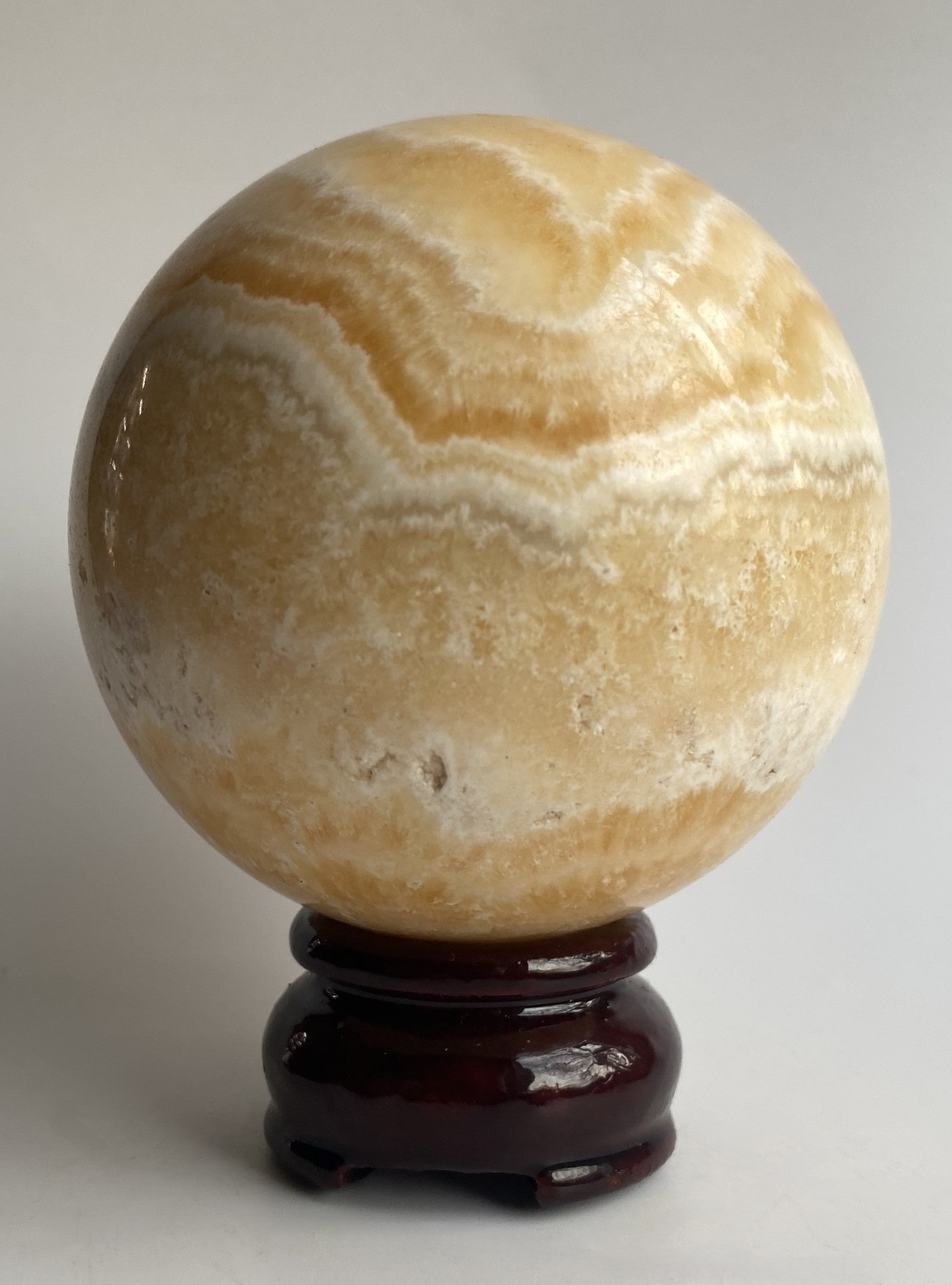 Sfera din mineral de calcit galben pe fundal alb sub lumina naturala