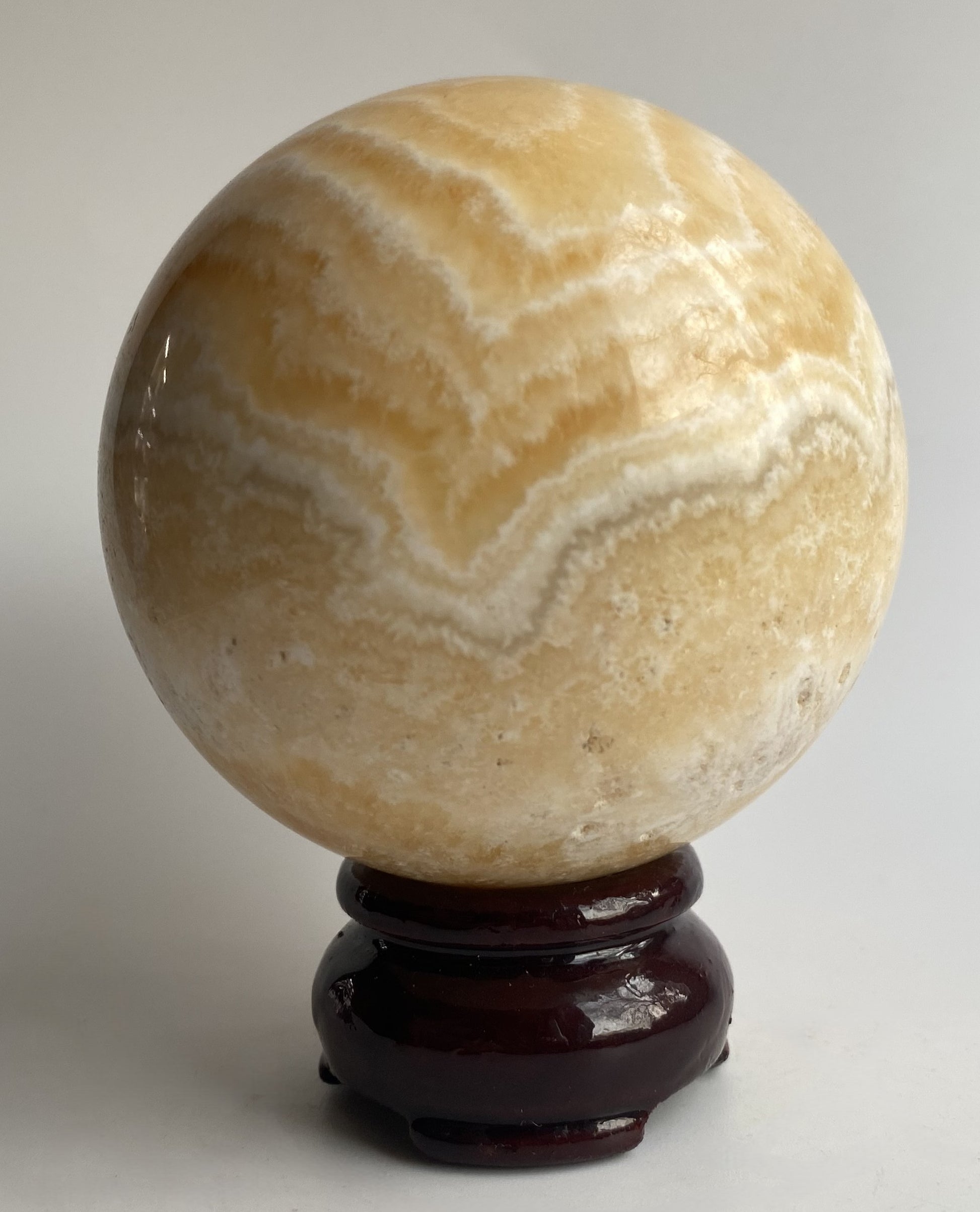 Sfera din mineral de calcit galben pe fundal alb sub lumina naturala