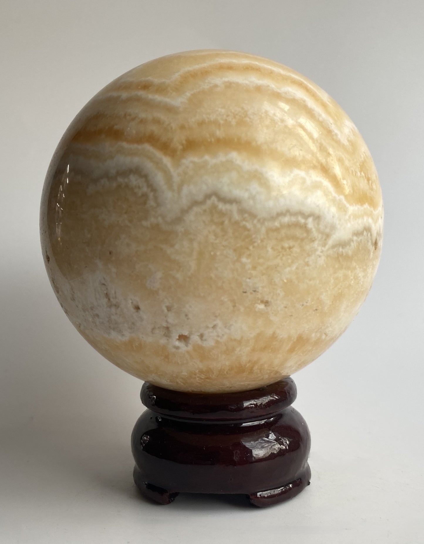 Sfera din mineral de calcit galben pe fundal alb sub lumina naturala