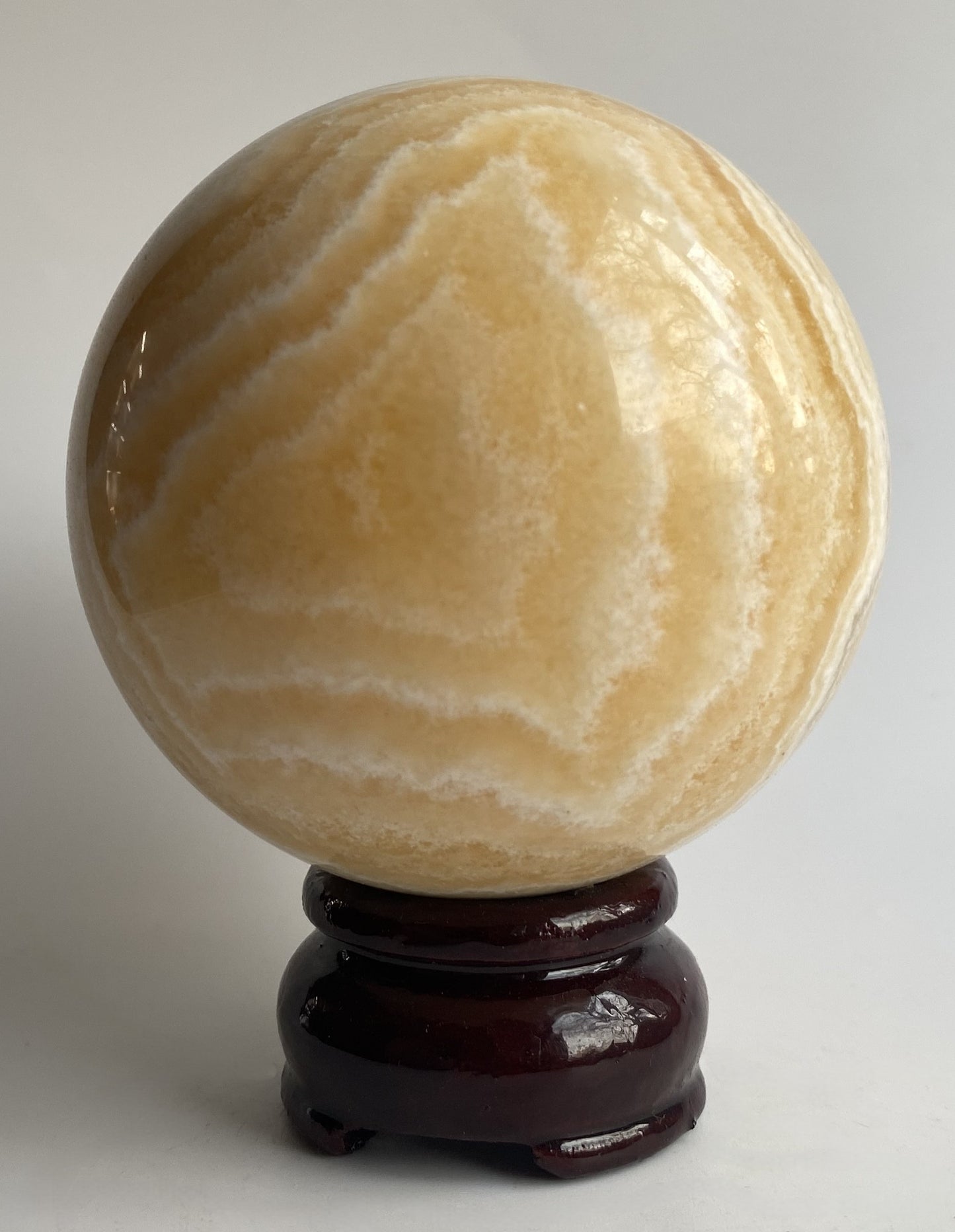Sfera din mineral de calcit galben pe fundal alb sub lumina naturala