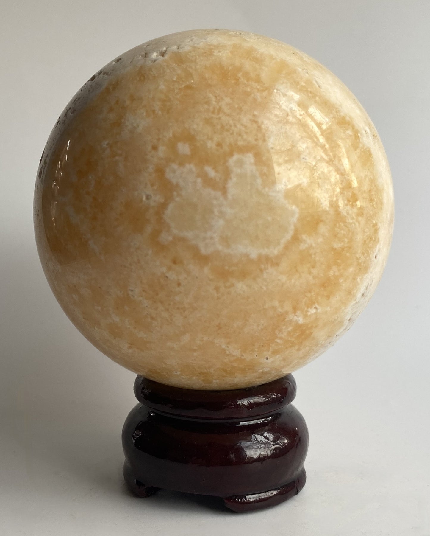 Sfera din mineral de calcit galben pe fundal alb sub lumina naturala