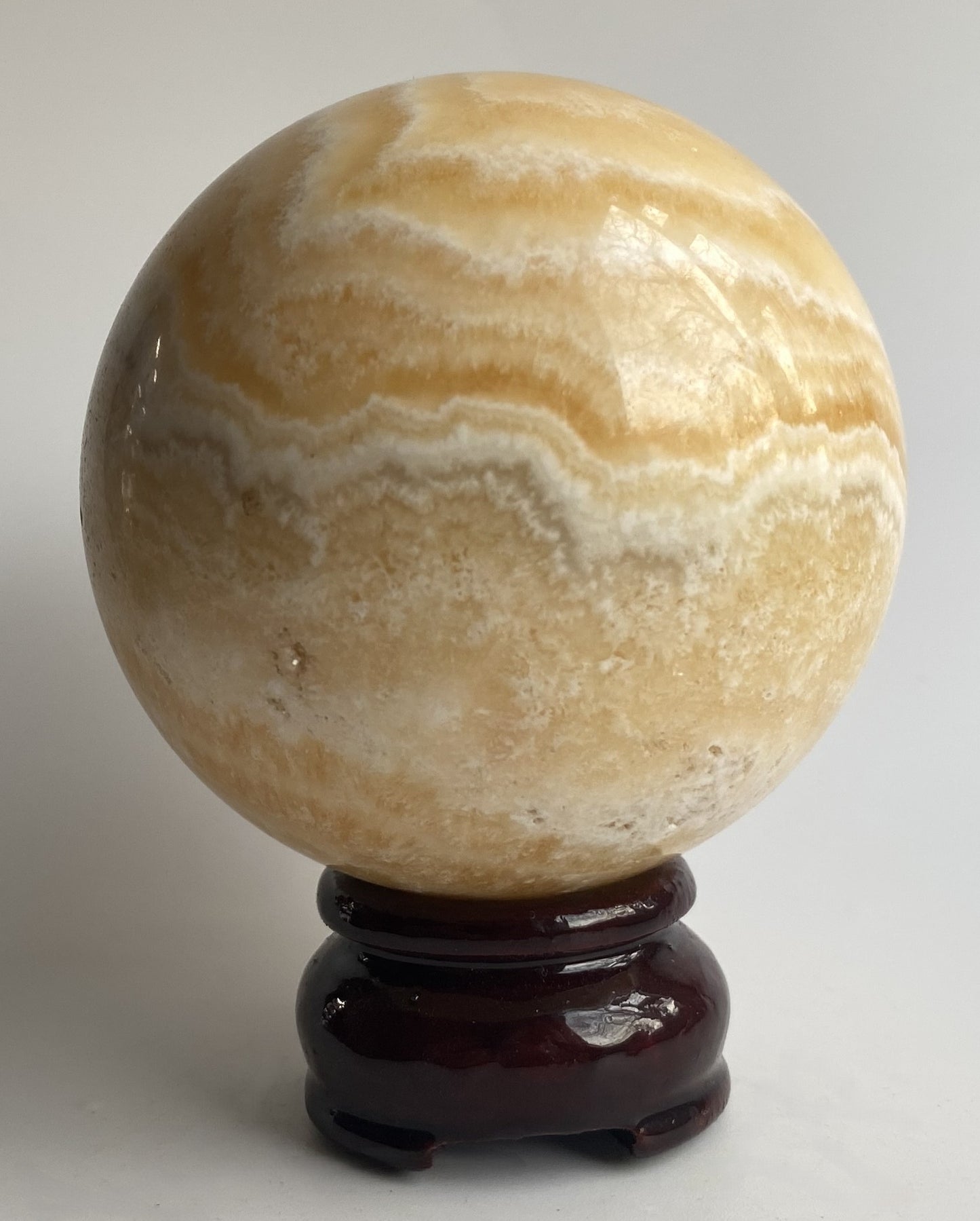 Sfera din mineral de calcit galben pe fundal alb sub lumina naturala