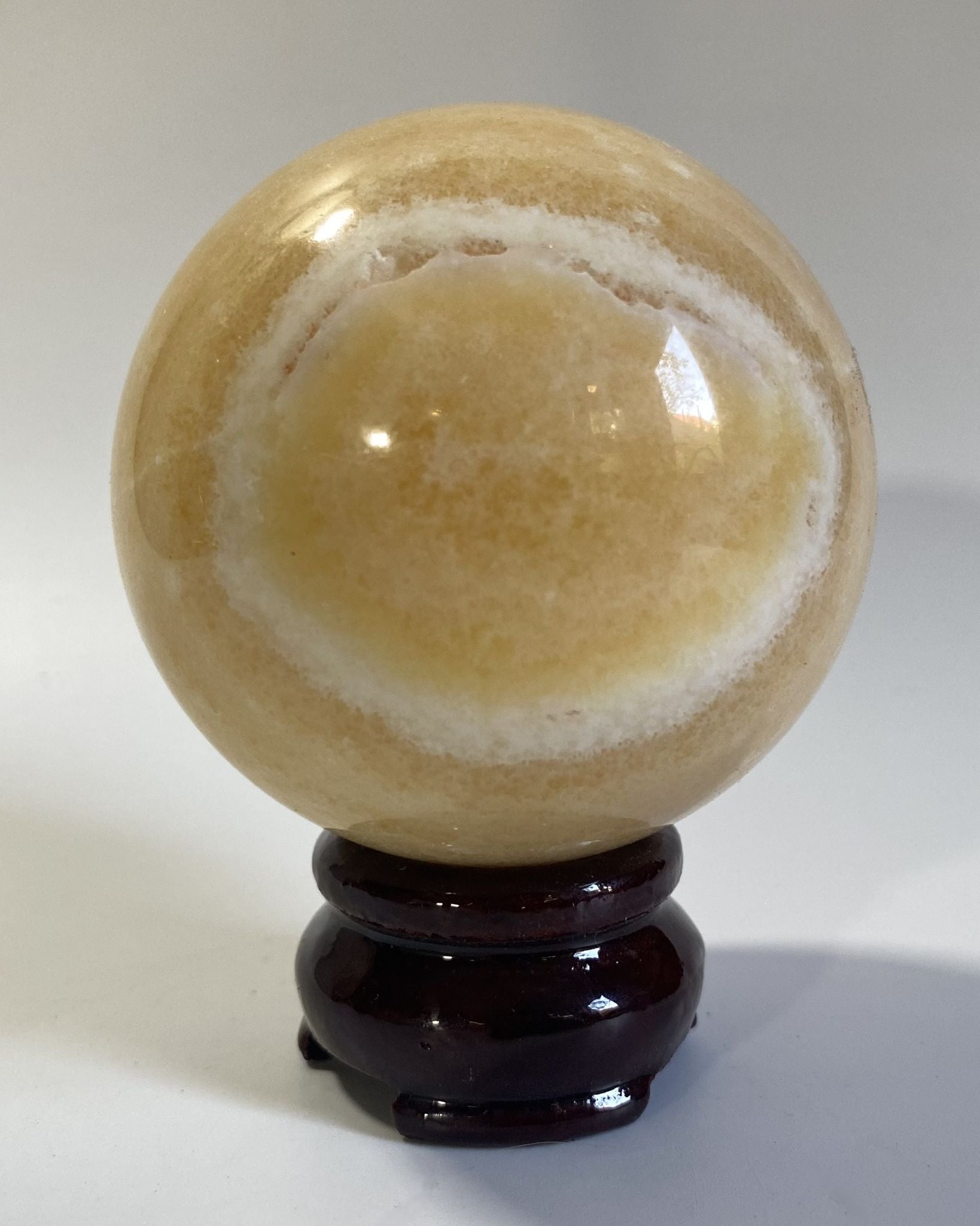 Sfera de 7.1cm din cristal de calcit galben pe suport din lemn cu fundal alb