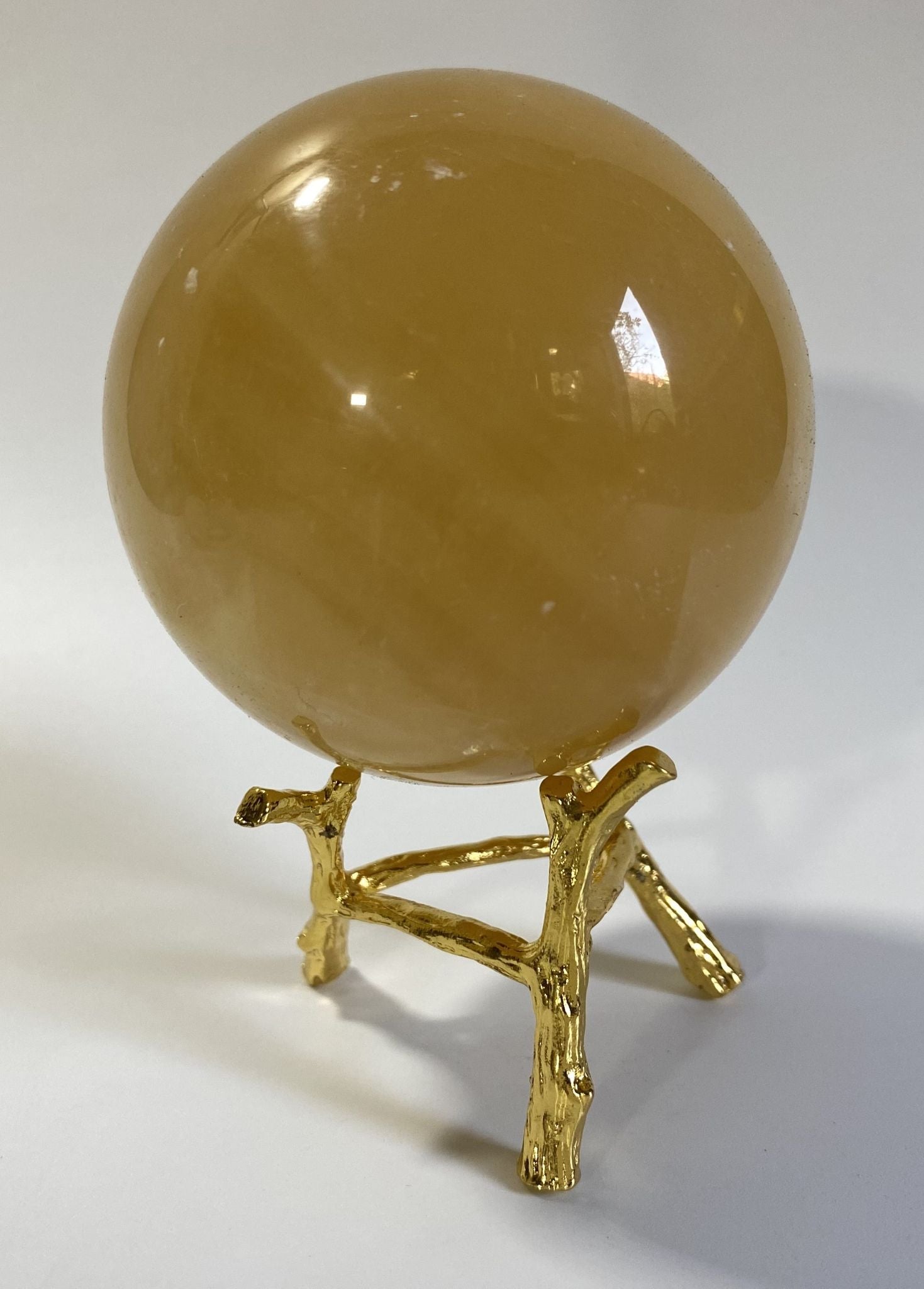 Sfera din cristal de calcit galben pe suport metalic cu fundal alb