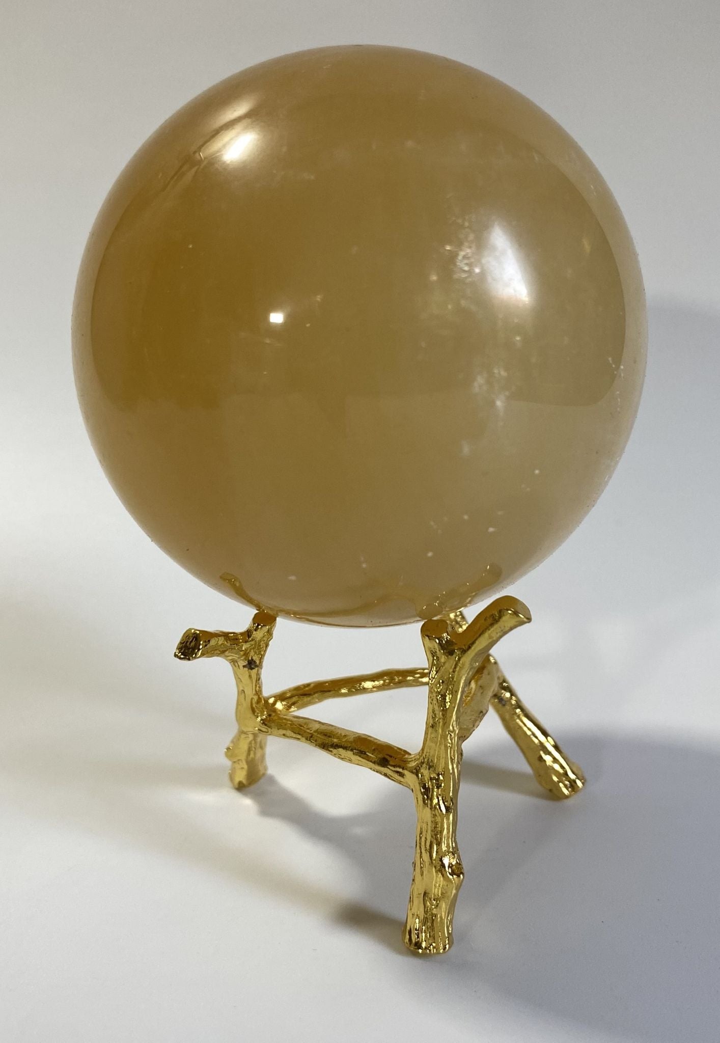 Sfera de 6.9cm din cristal de calcit galben pe suport metalic cu fundal alb