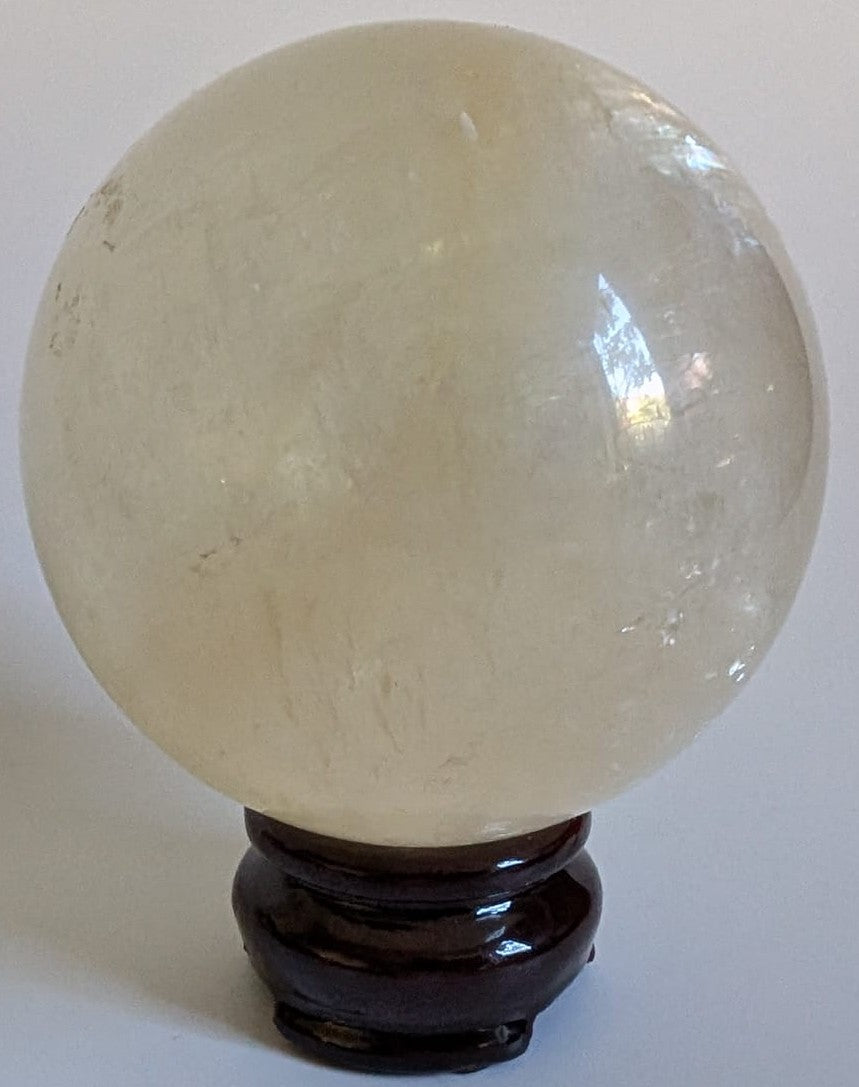 Sfera de 7.5cm din piatra semipretioasa de calcit Islanda pe suport din lemn cu fundal alb