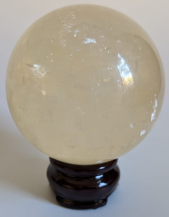 Sfera de 7.5cm din cristal de calcit Islanda pe suport din lemn cu fundal alb