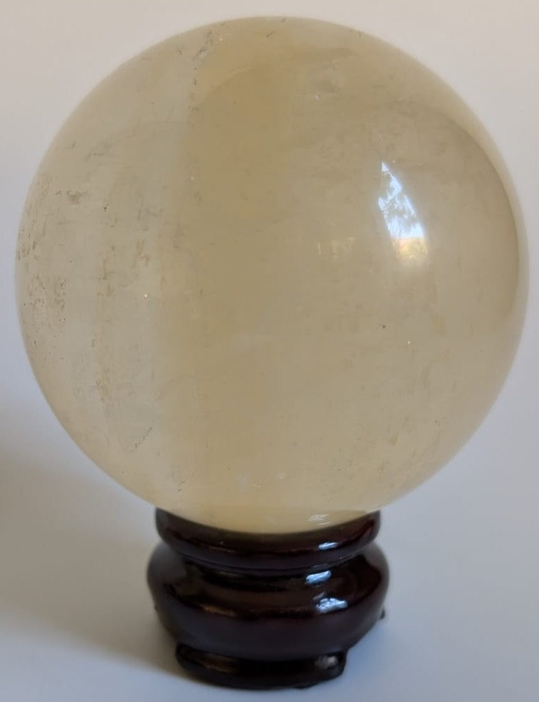 Sfera decorativa de 7.5cm din cristal de calcit Islanda pe suport din lemn cu fundal alb