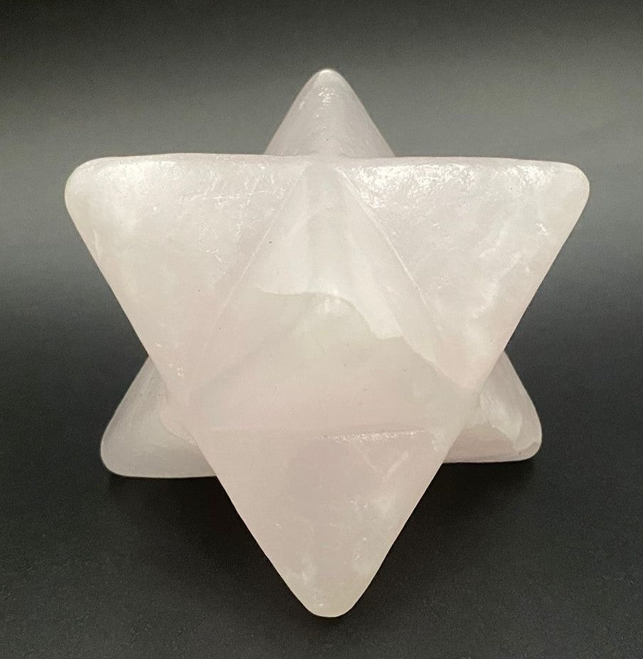 Merkaba din cristal de calcit roz pe fundal negru