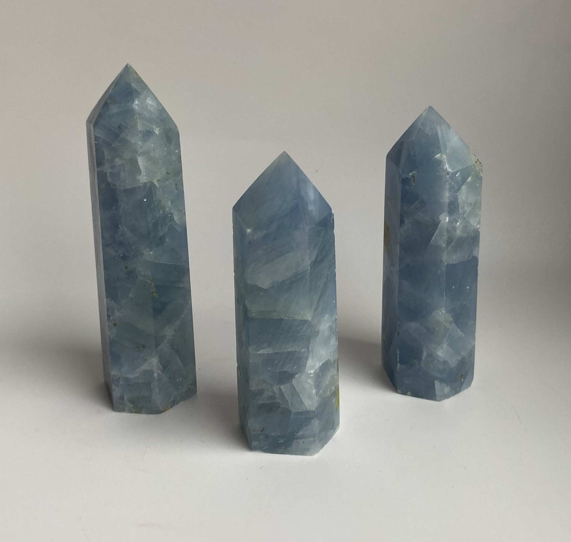 Set of three blue calcite obelisks semi-precious stones on white background