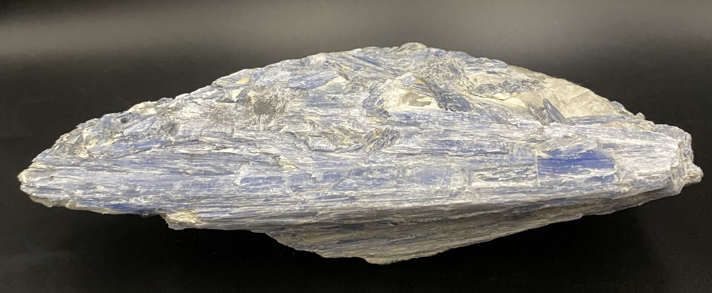 Piatra bruta din mineral de cianit pe fundal negru sub lumina artificiala